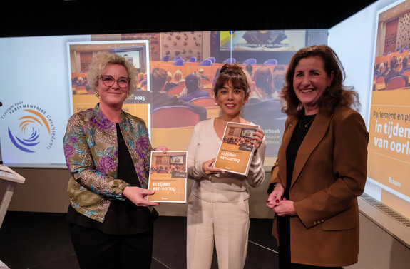 Eerste Kamervoorzitter Mei Li Vos en Ondervoorzitter Tweede Kamer Wieke Paulusma nemen boek in ontvangst uit handen van Ingrid van Engelshoven